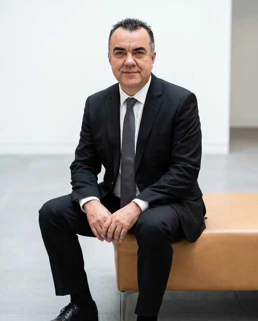 Stuart Newman seated in a black suit and white shirt